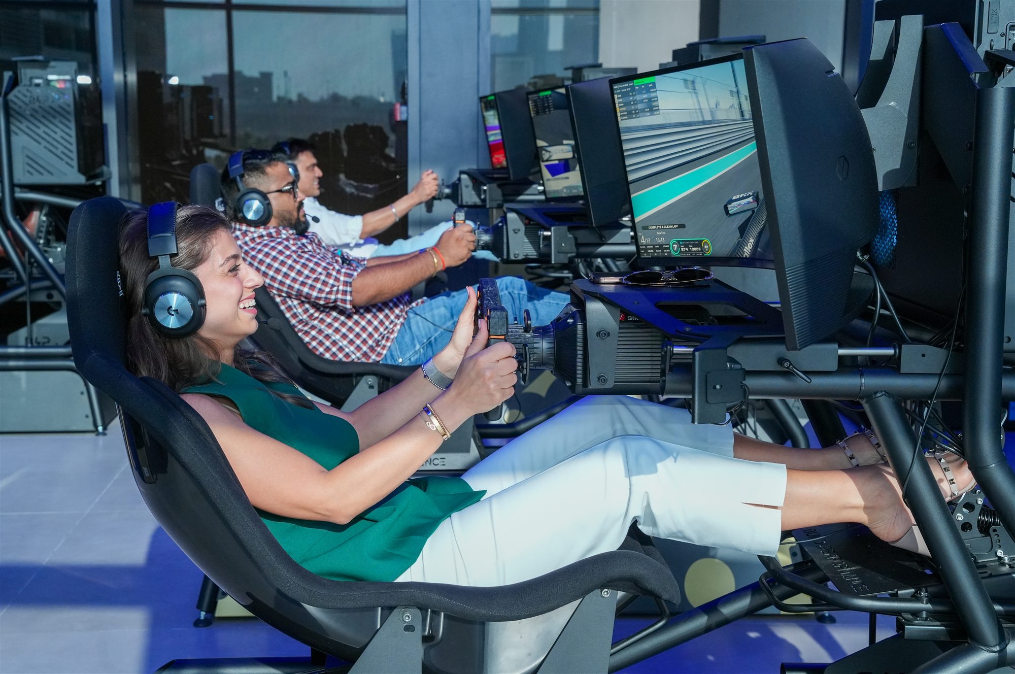 A smiling guest racing on a Racecraft simulator rig alongside other drivers, mid-session