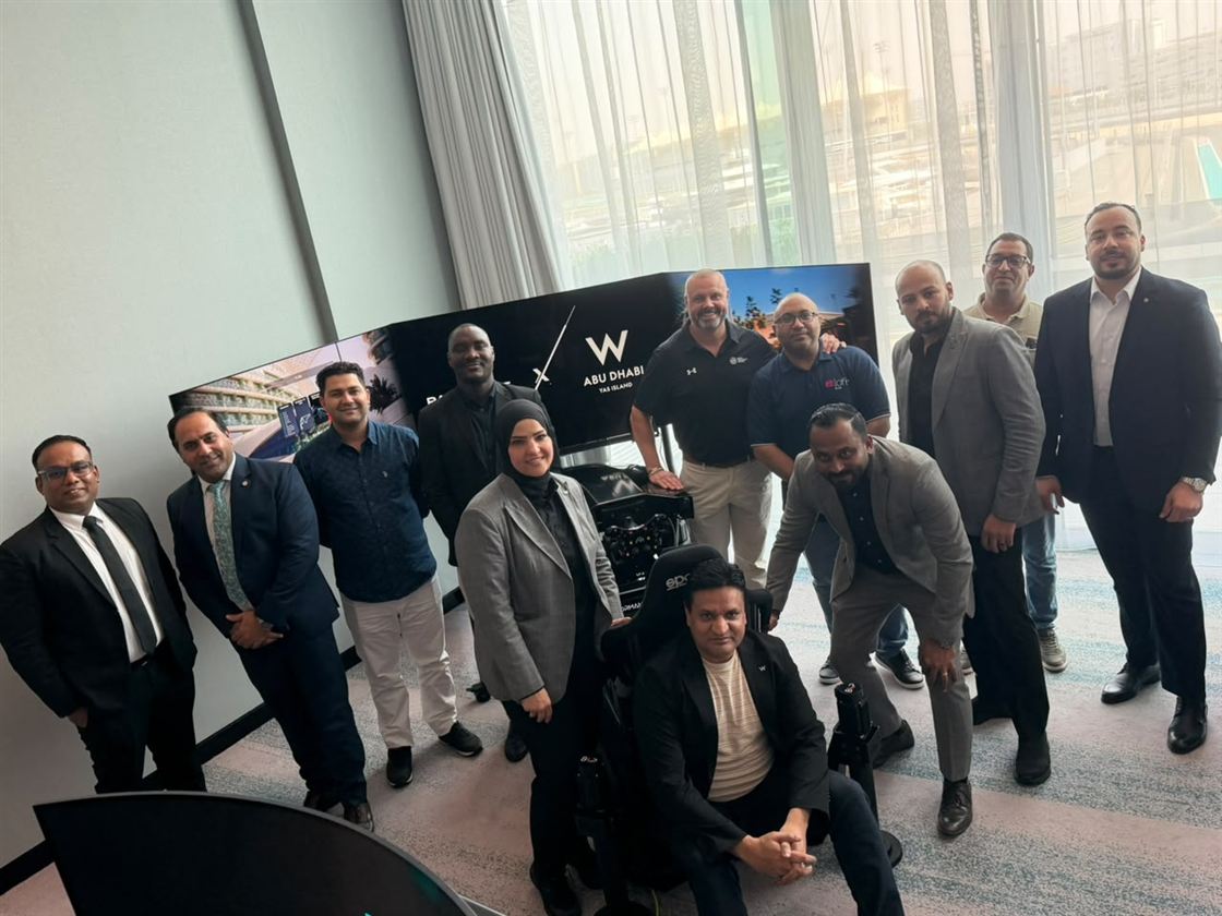 A group photo beside a Racecraft simulator at W Abu Dhabi - Yas Island