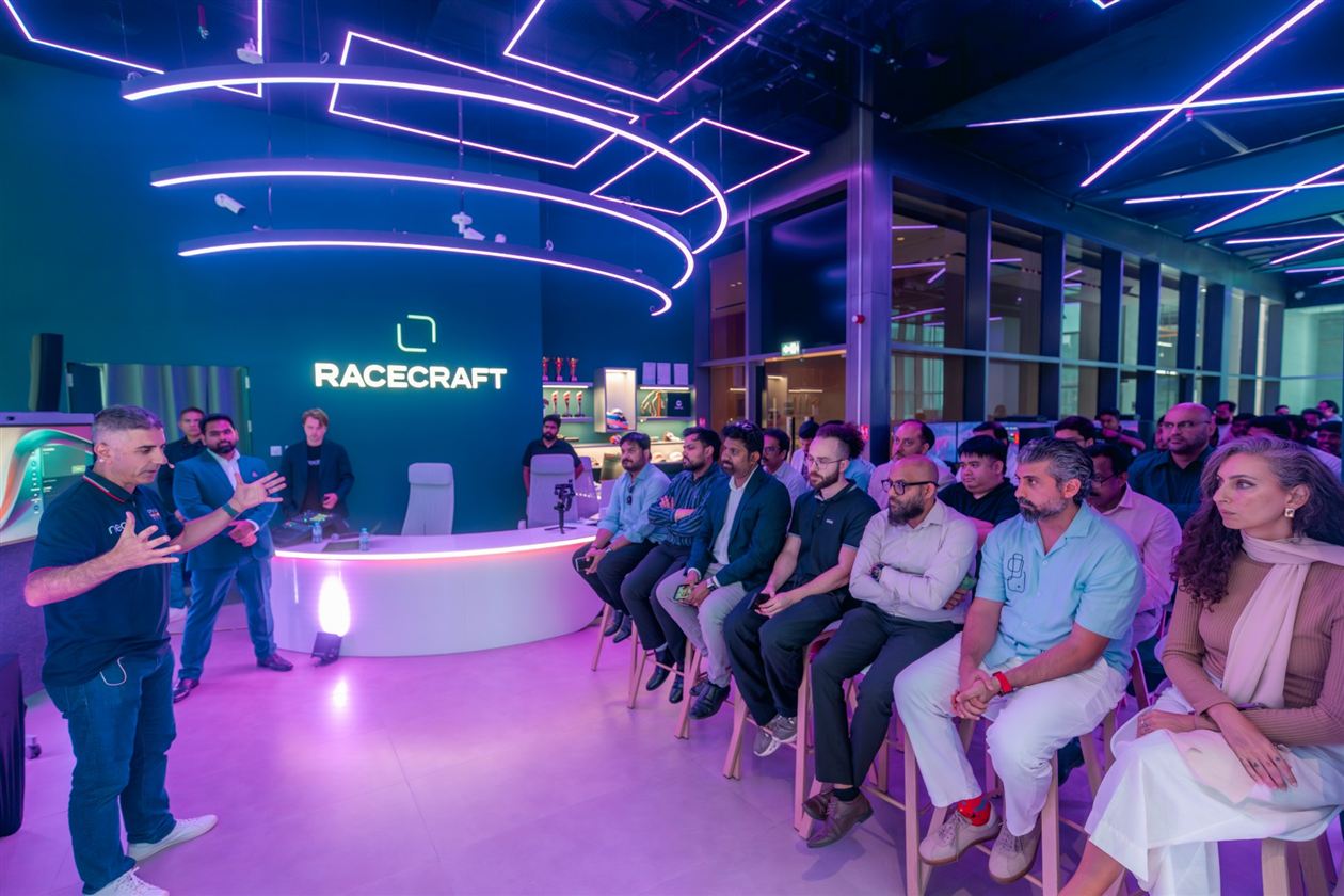 A speaker addressing an audience in front of the Racecraft wall